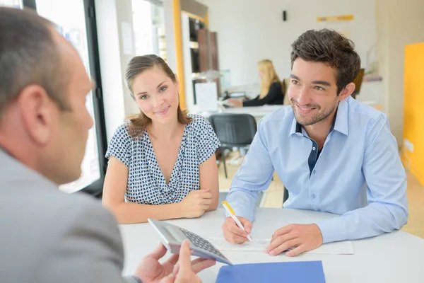 Professional financial advisors team in modern office having meeting with diverse clients discussing loan documents